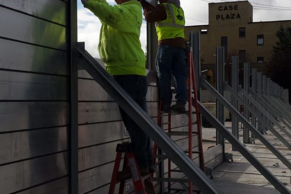 Two workers install flood planks between flood posts and struts in Fargo, ND.